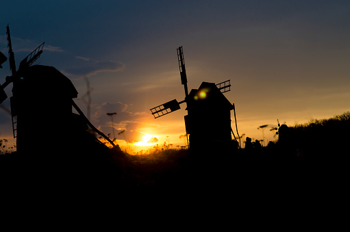 Silhouettes of old windmills on the background of bright blue sky sunset. Ukraine