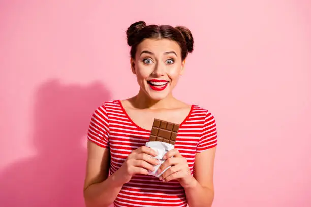 Photo of Portrait of her she nice cute charming crazy attractive lovely winsome cheerful cheery girl wearing striped t-shirt holding in hands desirable dessert isolated over pink pastel background