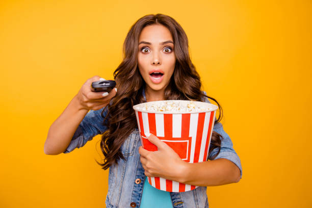 close up photo beautiful her she lady yell scream shout hold big large popcorn box stupor staring change channel wear blue teal green short dress jeans denim jacket clothes isolated yellow background - remote television movie box imagens e fotografias de stock