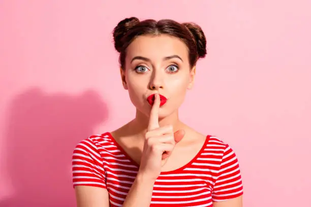 Close up photo beautiful she her lady pretty buns bright pomade lipstick arm hand finger lips asking not talk tell speak fellow friend wear casual striped red white t-shirt isolated pink background.