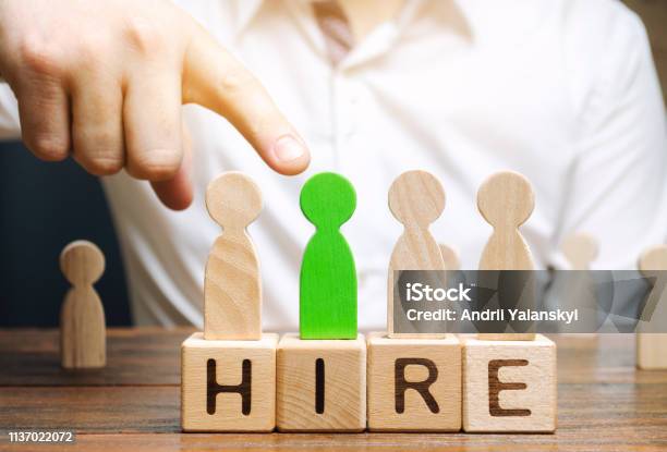 Wooden Blocks With The Word Hire Headhunter Selects A Person From The Crowd Good Choice Human Resource Management Recruiting Headhunting Hiring Employees Businessman Points To The Green Man Stock Photo - Download Image Now