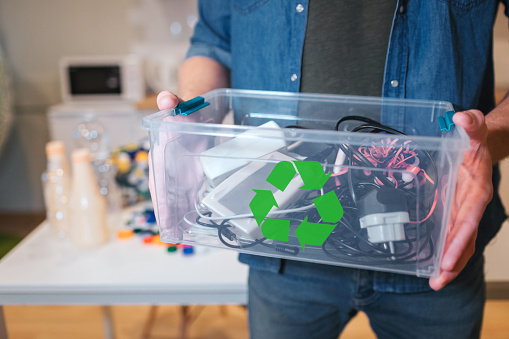 Concepto de reciclaje. Un residuo electrónico en el reciclaje contaner Close-up. El hombre responsable protege el medio ambiente mientras ordena los desechos en el hogar photo