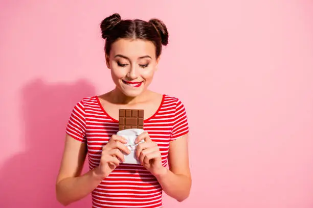 Photo of Portrait of her she nice cute charming attractive lovely winsome cheerful hungry girl wearing striped t-shirt holding in hands favorite desirable fresh dessert isolated over pink pastel background