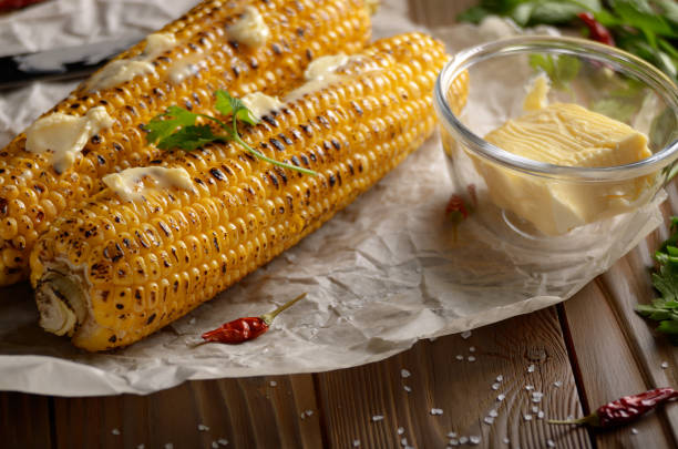 istock Kitchen table with grilled sweet corn cob under melting butter and greens on baking paper 1137022890