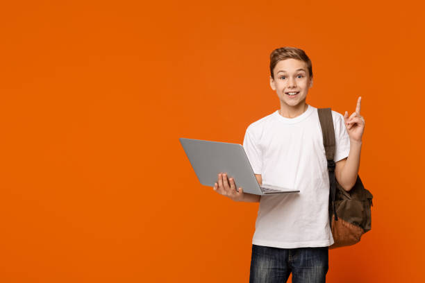 istock Cheerful boy holding laptop surprised with idea pointing finger up 1137026457