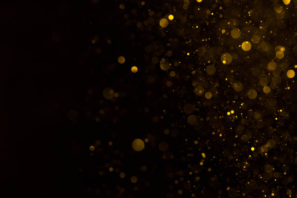 istock Glowing golden dust spark particles falling on black 1137028284