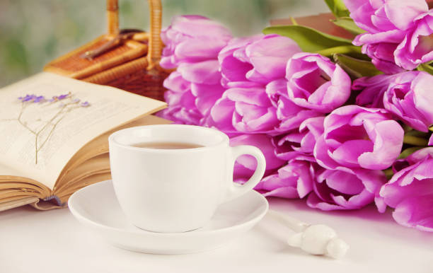 istock A cup of tea, book and violet tulips on the table 1137028452