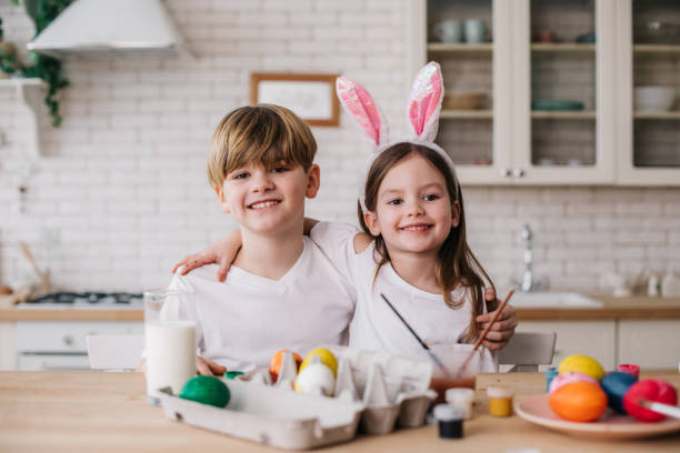 bambini carini sorridenti in posa per la macchina fotografica in cucina - easter easter egg paintbrush holding foto e immagini stock
