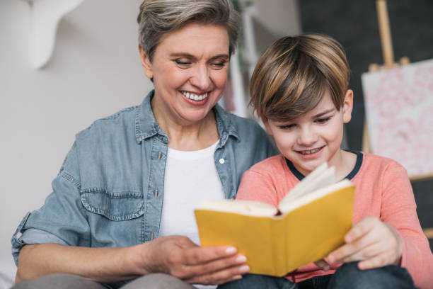 niski kąt uśmiechniętego wnuka spędzającego czas z babcią w domu - grandmother reading child grandson zdjęcia i obrazy z banku zdjęć