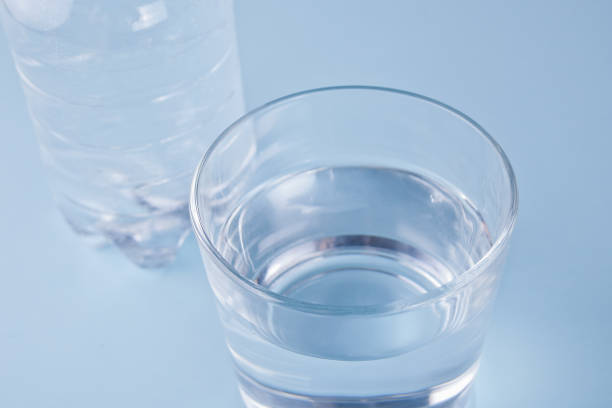 istock Glass and bottle with water on a blue background 1137028804