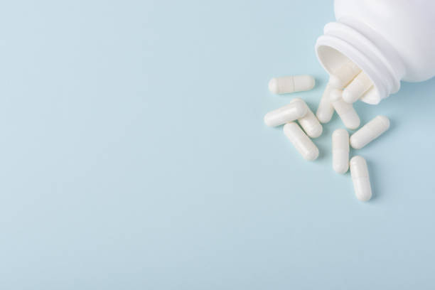 istock Pills capsules in white plastic bottle on blue background 1137030253