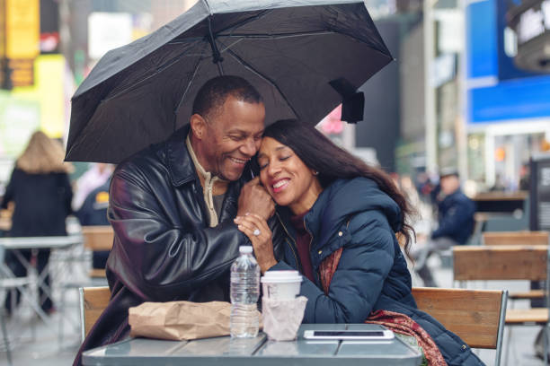 coppia matura in time square - candid women african descent umbrella foto e immagini stock