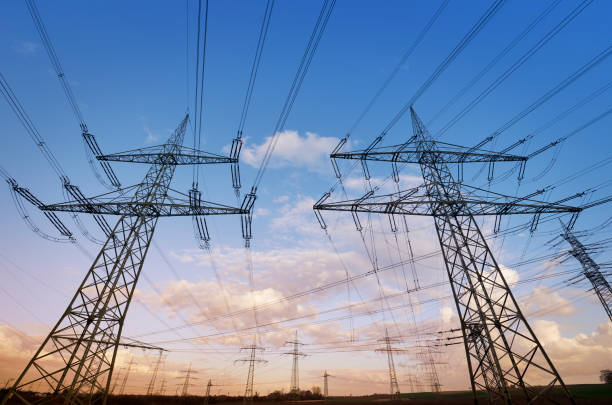 istock Two electricity pylons at sunset low angle view 1137032226