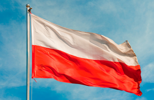 The Polish flag flutters on the mast against the cloudy sky. Wind, clouds and flag