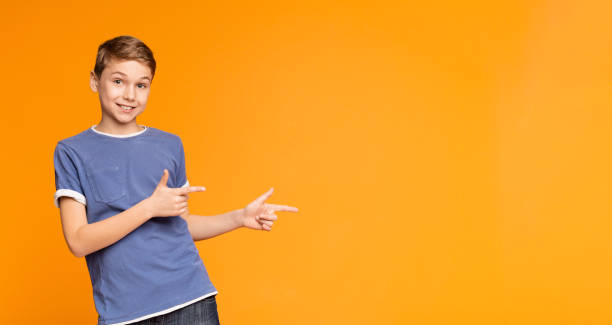 istock Cute little boy pointing away on orange background 1137034276