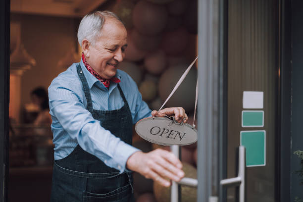 istock Joyful cafe owner putting open sign on glass door 1137035524