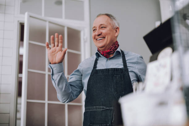 istock Joyful senior man in apron showing hello gesture 1137035596