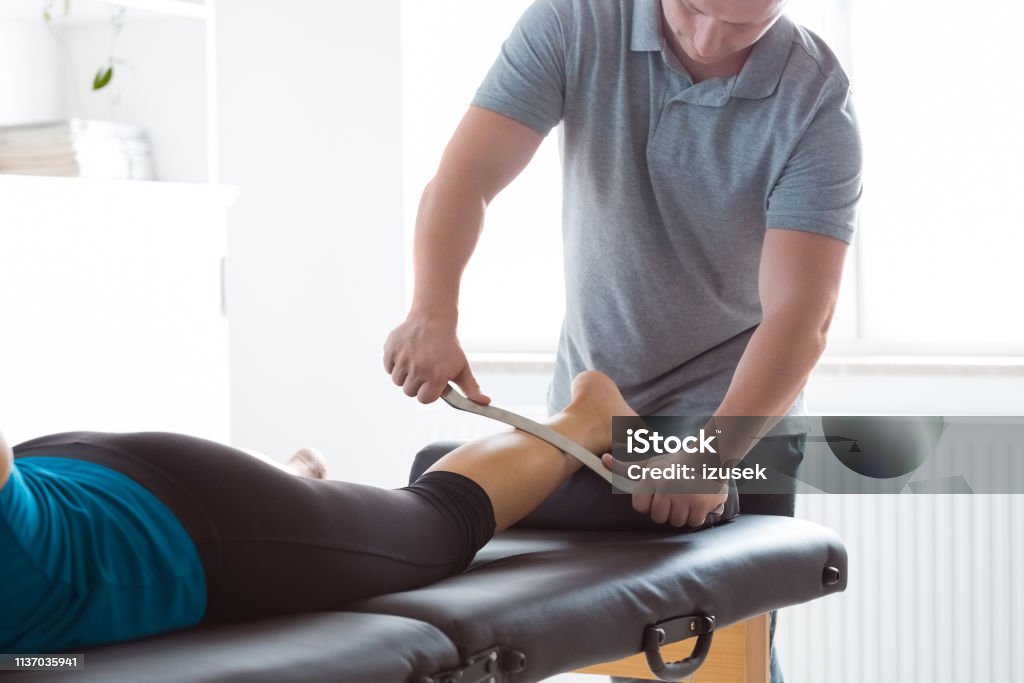 Physiotherapist massaging woman's leg using tools Physical therapist giving leg massage to young woman using tools. Close up of hands, unrecognizable people. Physical Therapist Stock Photo