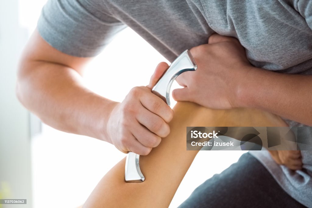 Physiotherapist massaging woman's leg using tools Physical therapist giving leg massage to young woman using tools. Close up of hands, unrecognizable people. Achilles Tendon Stock Photo