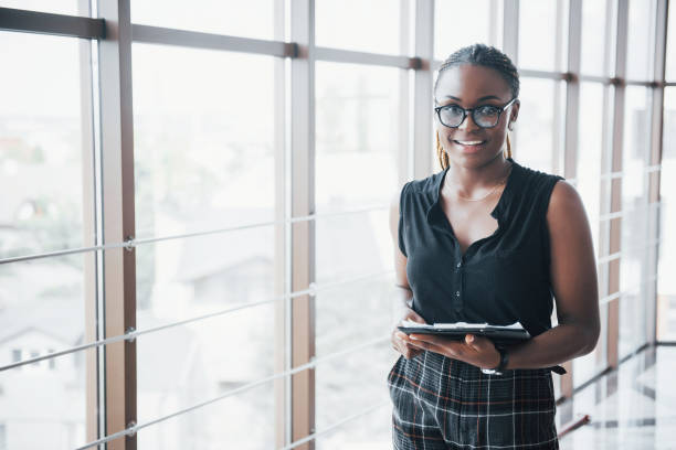 A thoughtful African American business woman wearing glasses holding documents A thoughtful African American business woman wearing glasses holding documents. prosperity stock pictures, royalty-free photos & images
