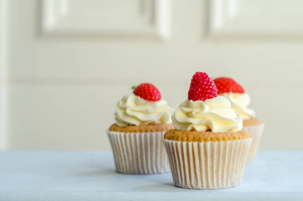 cupcake ghiacciati al forno a casa con bacche rosse - cream cheese food food and drink dessert foto e immagini stock