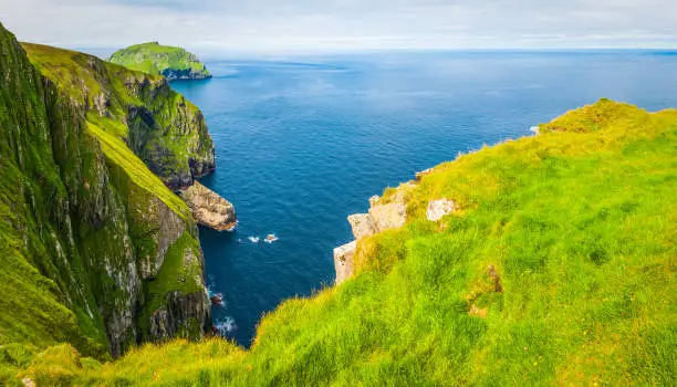 The green pastures and precipitous sea bird cliffs of St. Kilda, the remote island archipelago and UNSECO World Heritage Site beyond the Outer Hebrides of the Highlands of Scotland.