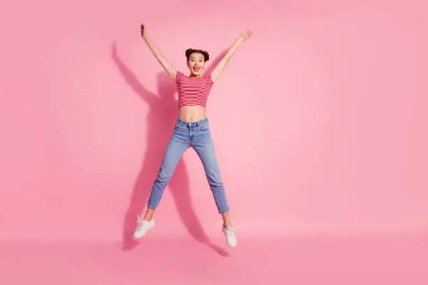 Full length body size photo yelling beautiful she her lady pomade lips jump high star shape best big great win fan wear casual jeans denim striped red white t-shirt sit floor isolated pink background.