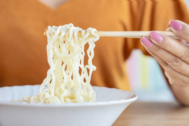 istock woman hand holding chopsticks eating noodle 1137040132