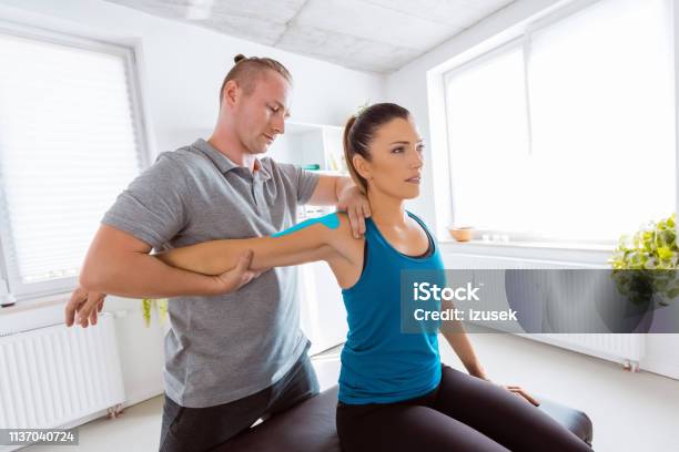 Physiotherapist Massaging Young Woman Stock Photo - Download Image Now - Elastic Therapeutic Tape, Adult, Occupational Therapy