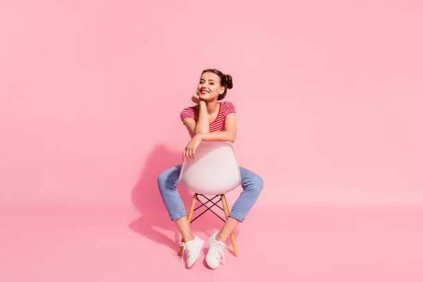 Photo of Nice-looking attractive glamorous magnificent lovely shine cheerful cheery girl wearing striped tshirt jeans sitting on chair having free time isolated over pink pastel background