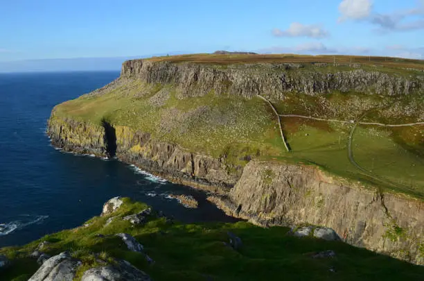 Sea cliff with pastures for grazing sheep at Neist Point in Scotland.