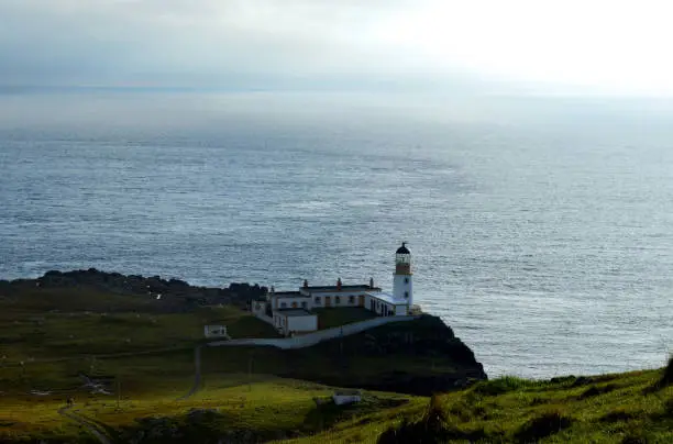 Scotland's Neist Point lighthouse with rolling hills and cliffs.