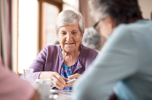 Shot of a senior woman playing cards in a retirement home during the day