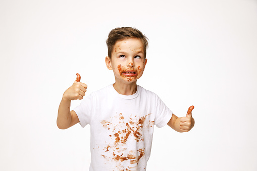 little boy with face and hands in chocolate shows super sign