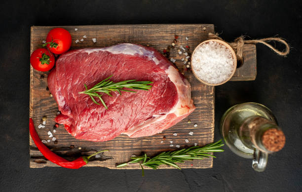 istock Raw fresh steak with herbs, on a cutting board, stone background, top view 1137052964