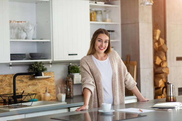 młoda kobieta stojąca w kuchni - domestic kitchen people fun lifestyles zdjęcia i obrazy z banku zdjęć