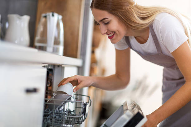 woman putting dishes into dishwasher - contemporary indoors lifestyles domestic room imagens e fotografias de stock