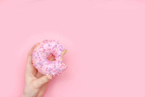 istock girl holding a glazed pink donut on a pink monochromatic background 1137065663