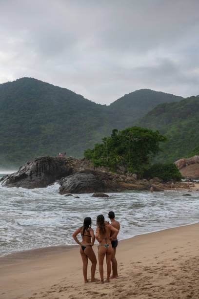 Three Brazilians stand on the beach called Praia do Meio in Trindade, Brazil. Trindade in near Paraty in Rio de Janeiro State. (March 18, 2019)