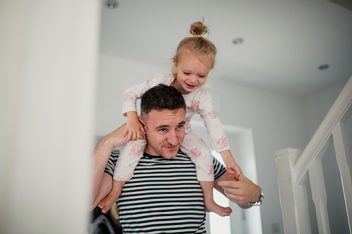 Father giving his daughter a piggyback ride as she laughs.