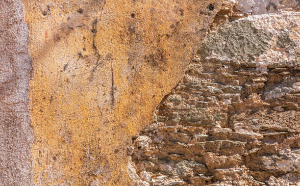 istock Old, distressed stone wall, building facade. Painted and faded, orange color masonry, texture background 1137069522
