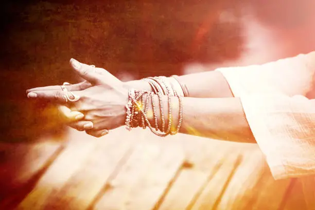 woman hands in yoga symbolic gesture mudra  lot of bracelets and rings  mix with textures closeup