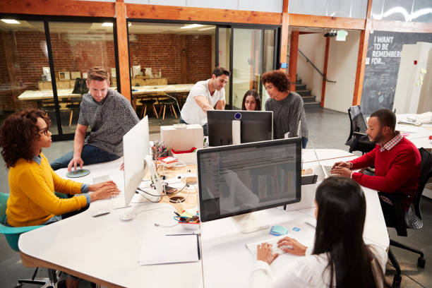 gekleicht gekleidetes business team arbeitet an den desken im modernen open plan office - großraum stock-fotos und bilder