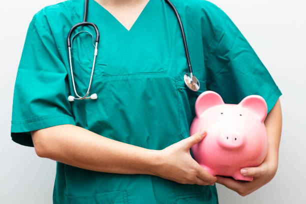 Medical Costs Doctor with piggy bank in hand representing medical costs operating budget stock pictures, royalty-free photos & images