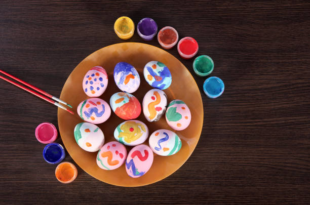 istock painted Easter eggs, paintbrush and paint on the table. preparation for Easter. wooden table. 1137078892