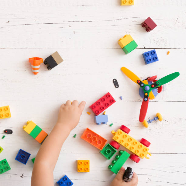 istock Top view on child's hands playing with colorful plastic toy bricks and small details on white wooden table background 1137083284