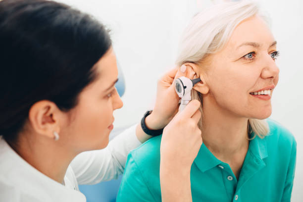mujer madura haciendo examen de oído en la clínica - otoscopio fotografías e imágenes de stock