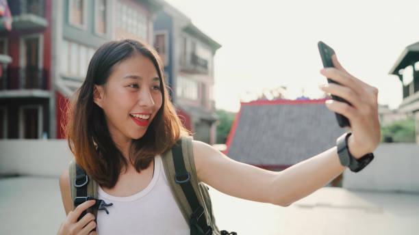 istock Cheerful beautiful young Asian backpacker blogger woman using smartphone taking selfie while traveling at Chinatown in Beijing, China. Lifestyle backpack tourist travel holiday concept. 1137092253