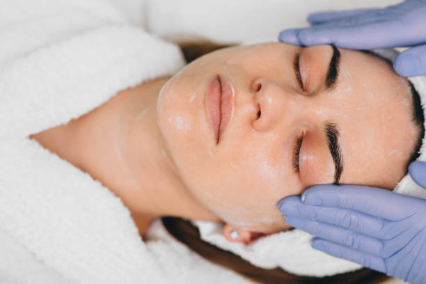 woman receiving facial treatment at beauty salon. Exfoliation beautiful woman having her face pampered at beauty salon by her beautician Mask stock pictures, royalty-free photos & images