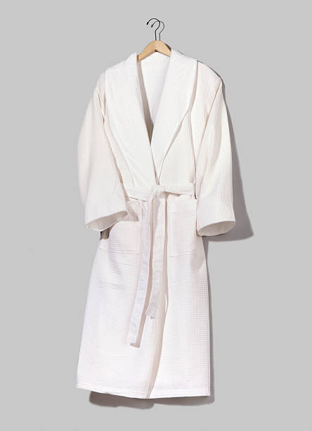 A white hung up bathrobe on a grey wall plush white spa bathrobe isolated on grey background bathrobe photos stock pictures, royalty-free photos & images